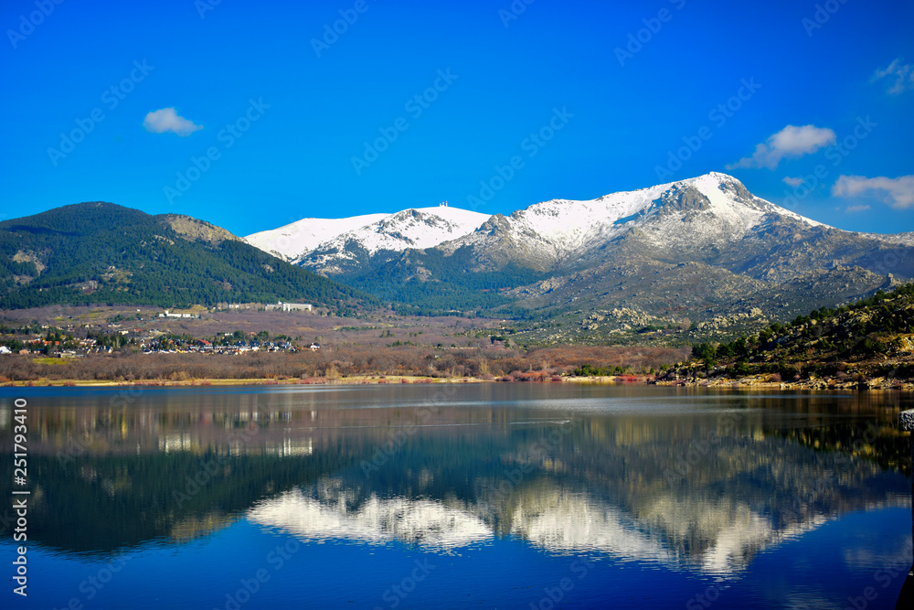 Montañas nevadas reflejadas en un lago azul de aguas tranquilas en un dia soleado de primavera