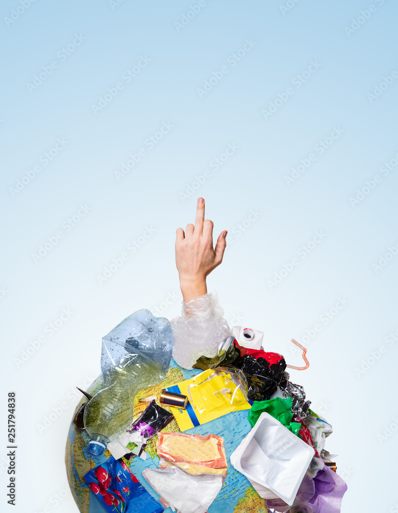 Obraz premium An earth globe covered with trash and male hand showing middle finger over white background, the concept of ecology problem and World Environment Day. Photo with message for social advertising, place