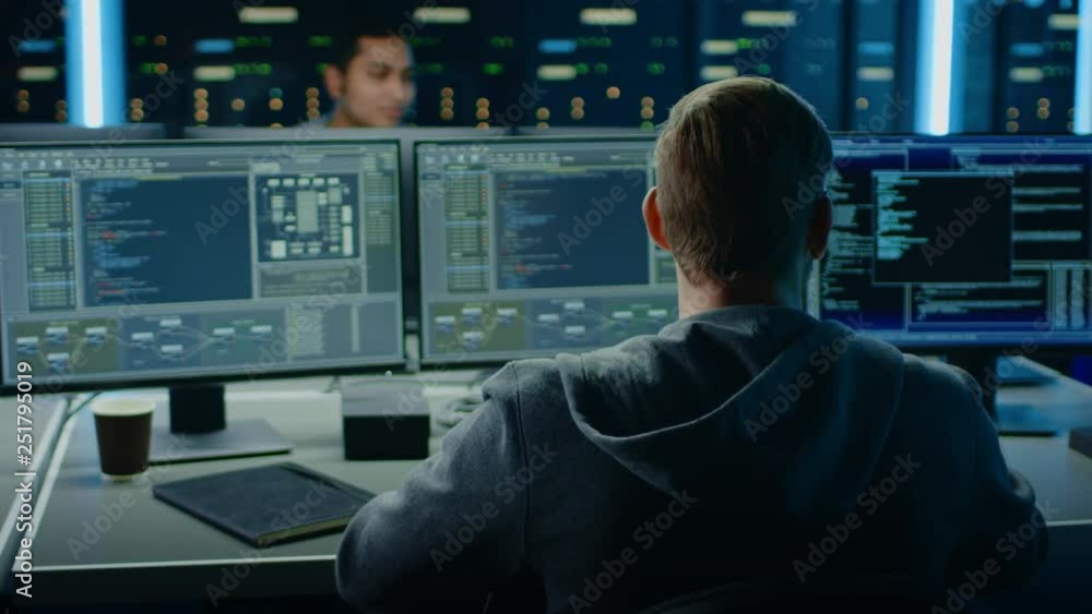 IT Specialist Works on Personal Computer with Screens Showing Software Program with Coding Language Interface. In the Background Technical Room of Data Center with Professional Working