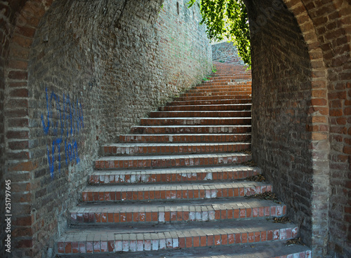 Red bricks stairway tunnel going up with light at the end