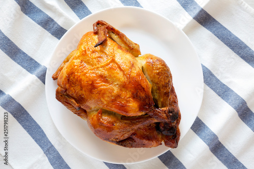 Homemade tasty rotisserie chicken on white plate, top view. Flat lay, overhead, from above. photo