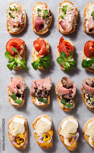Different types of bruschetta on a gray concrete background