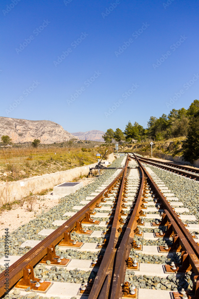 A railroad switch track with traffic signs, mountains and trees in the background A railroad switch track with traffic signs, mountains and trees in the background