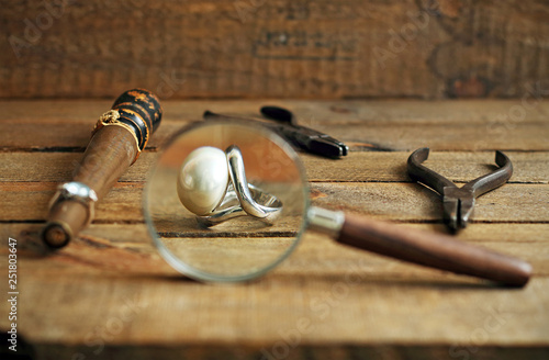 Rings, tools and magnifying glass on wood