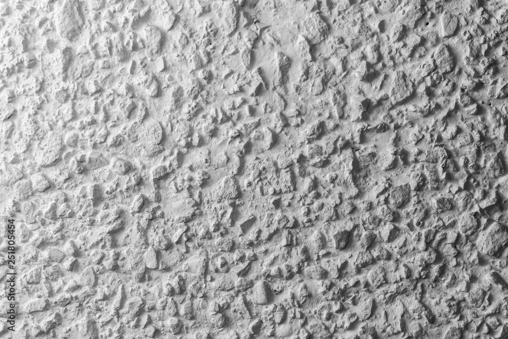 Black and white whitewashed concrete wall interspersed with stones