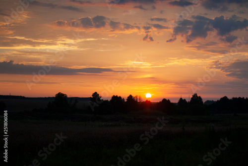 View of a Beautiful Sunset and Sky with dramatic clouds over a Silhouetted Land Horizont.