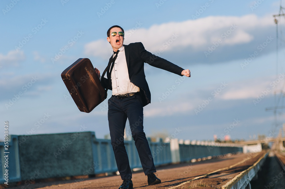Happy caucasian man runs along the train station and waving his suitcase. The concept of good luck in business, vacation, good news. Happy caucasian man runs along the train station and waving his suitcase. The concept of good luck in business, vacation, good news.