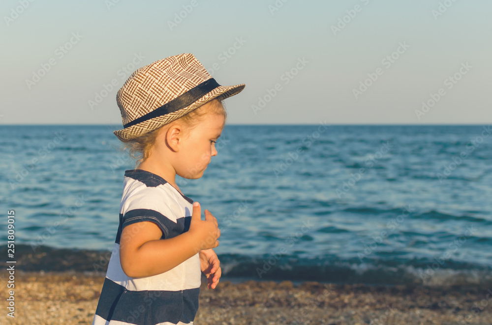 Little girl in a hat walks along the seashore Little girl in a hat walks along the seashore