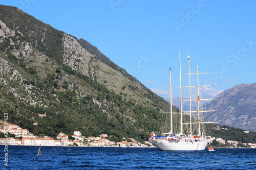 Beautiful pleasure craft against the backdrop of the mountains  the sea and the resort town with red tile roofs.