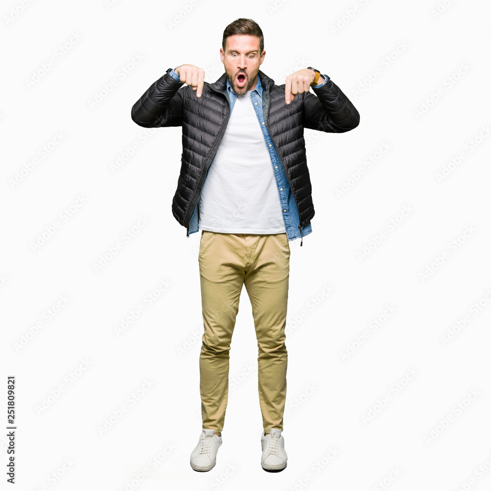 Handsome man wearing winter coat Pointing down with fingers showing advertisement, surprised face and open mouth Handsome man wearing winter coat Pointing down with fingers showing advertisement, surprised face and open mouth