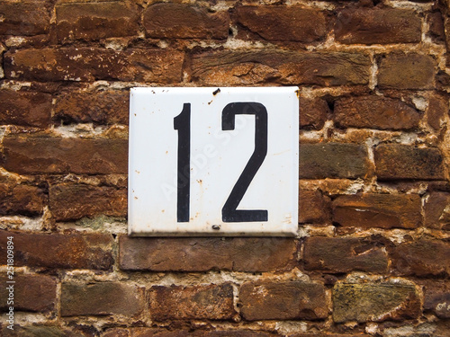 The number plate "twelve" on a brick wall