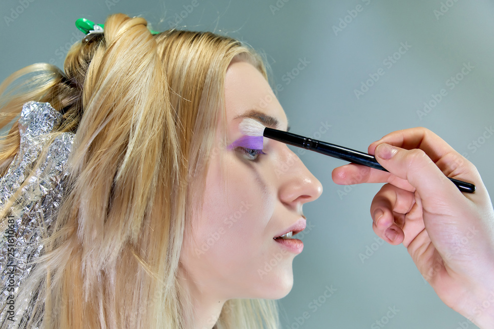Obraz premium Concept work of a beautician cosmetologist in with office. Makes hair, applies makeup on a gray background.