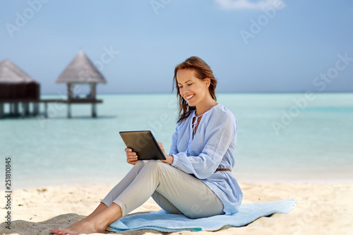 technology, people and leisure concept - happy smiling woman with tablet pc computer over tropical beach and bungalow on maldives background