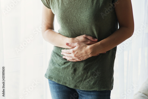 young woman with hand on stomach suffering abdominal pain