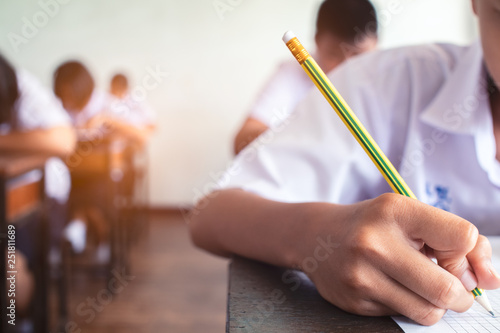 Close up to School student is taking exam and writing answer in classroom for education test concept