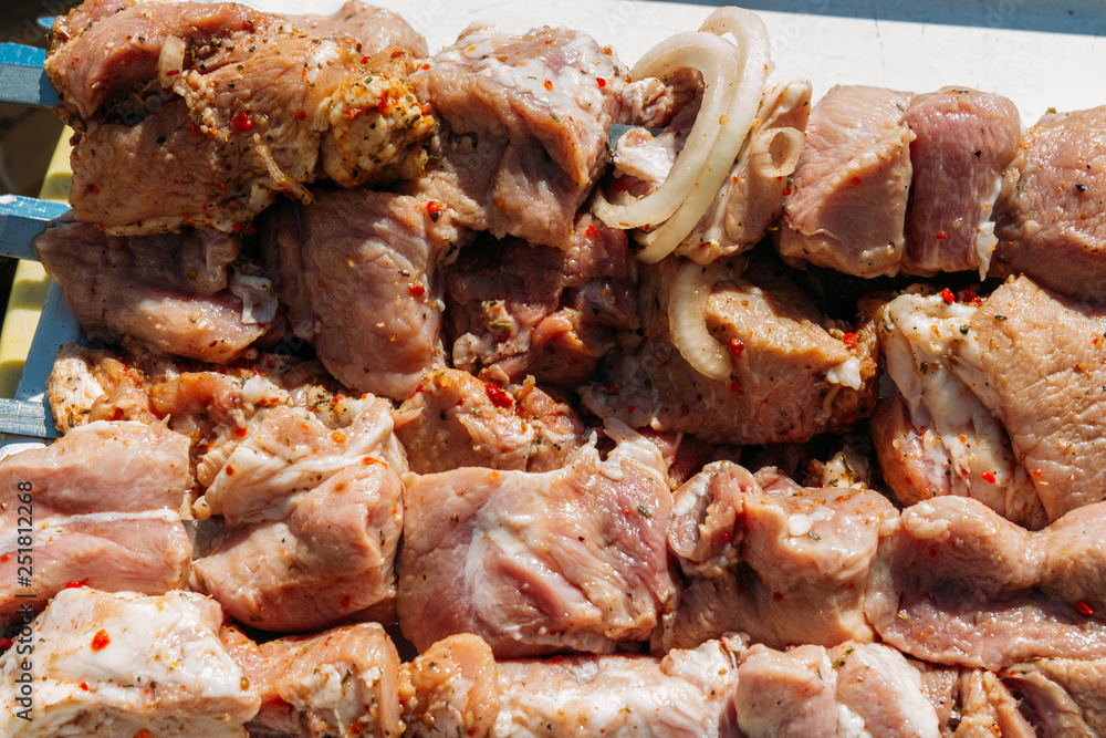 pieces of raw meat on skewers lies on a white tray. barbecue. cook meat with onions and peppers. pickled, picnic, street food pieces of raw meat on skewers lies on a white tray. barbecue. cook meat with onions and peppers. pickled, picnic, street food