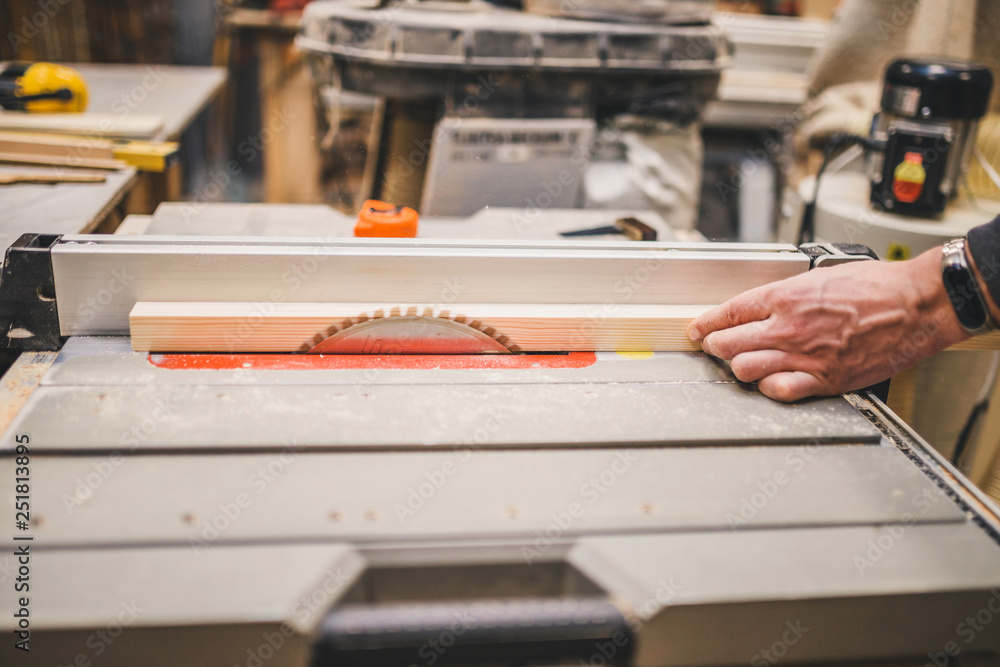 Carpentry workshop - carpenter works on a circular machine - cut bar Carpentry workshop - carpenter works on a circular machine - cut bar