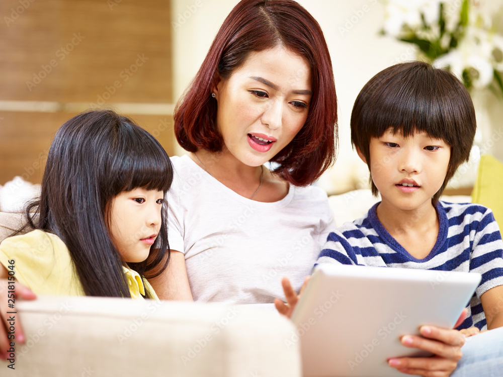 asian mother and two children using digital tablet together asian mother and two children using digital tablet together
