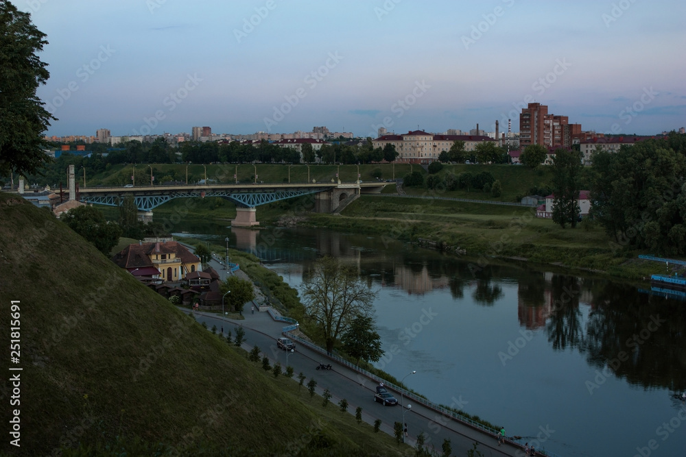 Grodno. Belarus. Evening landscape with the river Neman, the embankment of the river and the bridge on the background of a beautiful sky.