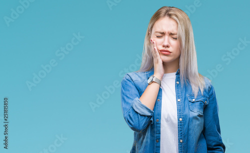 Young blonde woman over isolated background touching mouth with hand with painful expression because of toothache or dental illness on teeth. Dentist concept. photo