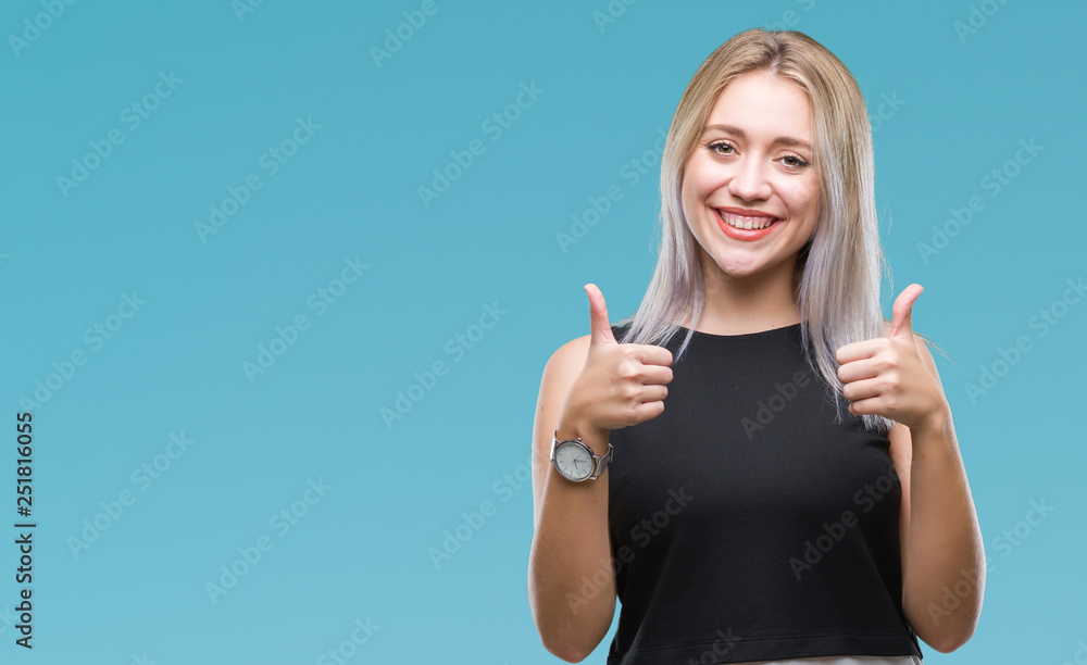 Young blonde woman over isolated background success sign doing positive gesture with hand, thumbs up smiling and happy. Looking at the camera with cheerful expression, winner gesture. Young blonde woman over isolated background success sign doing positive gesture with hand, thumbs up smiling and happy. Looking at the camera with cheerful expression, winner gesture.