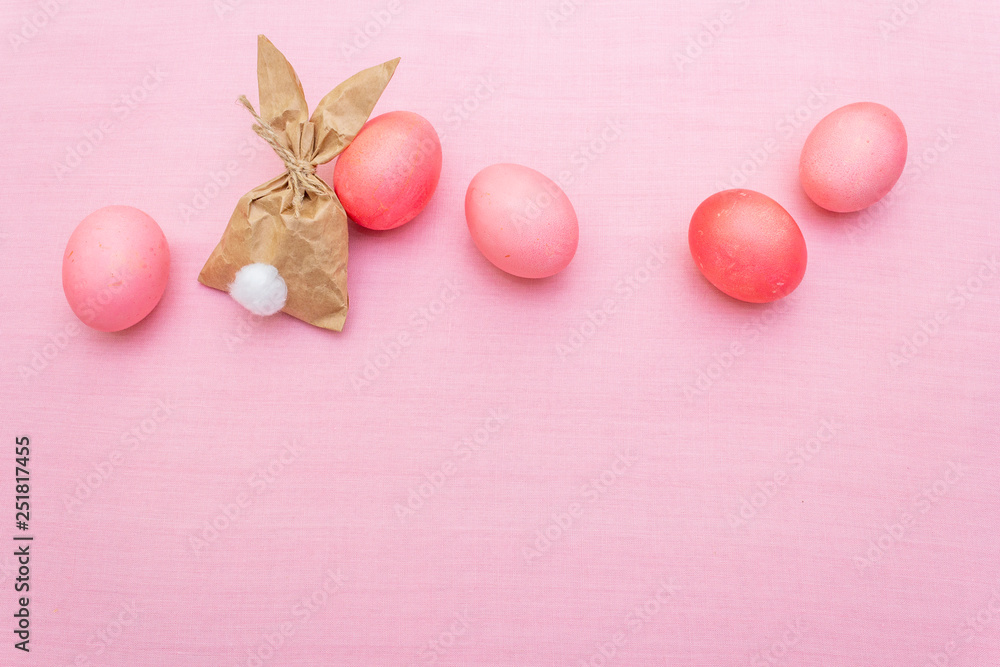 Easter bunny (rabbit) paper gift egg wrapping idea. Handicraft (homemade) concept for children (kids). On pink cloth (linen) background, top view