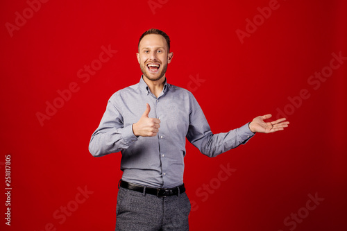 funny man giving thumb up sign over red background. people and emotion concept. © kaninstudio