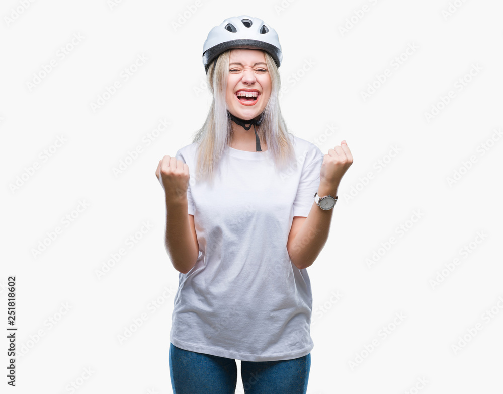 Young blonde woman wearing cyclist security helmet over isolated background celebrating surprised and amazed for success with arms raised and open eyes. Winner concept. Young blonde woman wearing cyclist security helmet over isolated background celebrating surprised and amazed for success with arms raised and open eyes. Winner concept.