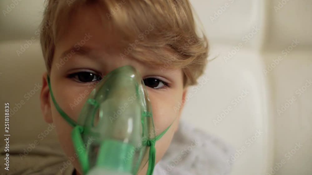 the boy makes inhalation while sitting on the bed.the child inhales