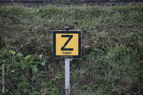 Sign in the side of a ditch to warn that there is an electricity cable sunken in the water photo