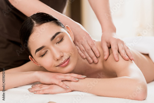 cropped view of masseur doing back massage to beautiful woman
