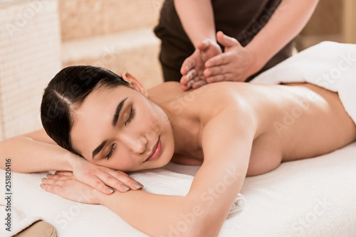 selective focus of masseur doing back massage to beautiful asian woman