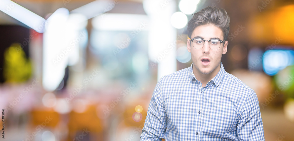 Fototapeta premium Young handsome man wearing glasses over isolated background afraid and shocked with surprise expression, fear and excited face.