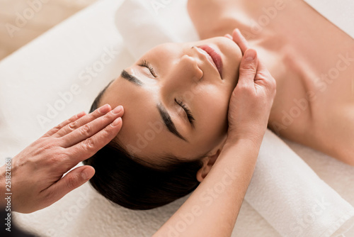 attractive asian woman getting face massage with closed eyes at spa