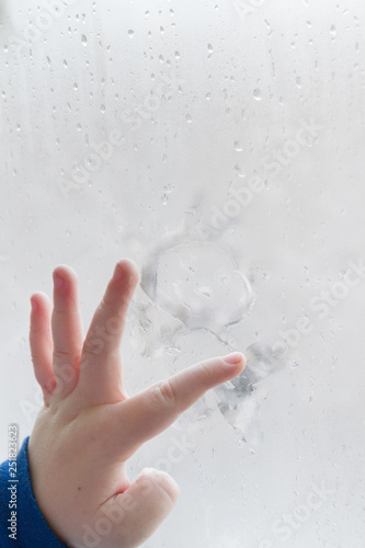 Obraz na płótnie The child's hand draws a man on a frozen misted window in winter w salonie