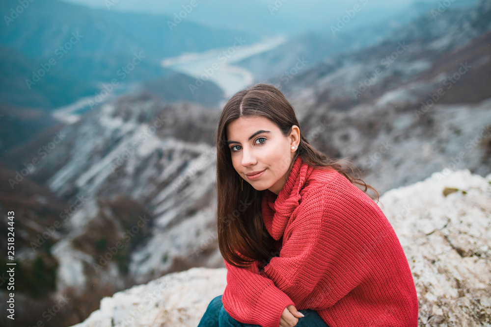 Portrait of Beautiful Young Girl in a cosy red sweater on Mountain top