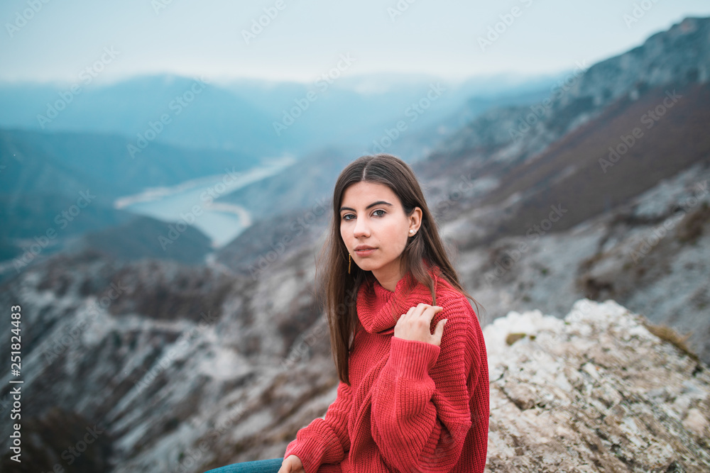 Portrait of Beautiful Young Girl in a cosy red sweater on Mountain top