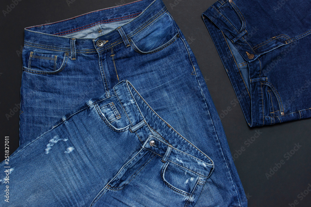 Set of men's and women's blue jeans on black background top view flat lay. Detail of nice blue jeans. Jeans texture or denim background. Trend clothing. Beauty and fashion, clothing concept. Set of men's and women's blue jeans on black background top view flat lay. Detail of nice blue jeans. Jeans texture or denim background. Trend clothing. Beauty and fashion, clothing concept.