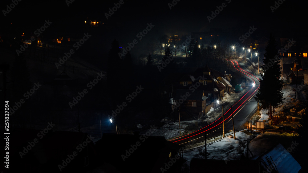 A wonderful panorama of the night mountain village of Ukraine with car tracks