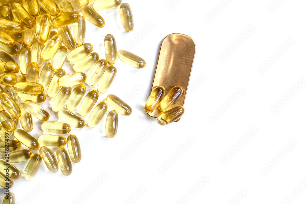 A lot of fish oil omega 3 6 9 capsules on a brass golden spoon. sports nutrition healthy food and lifestyle top view place for text