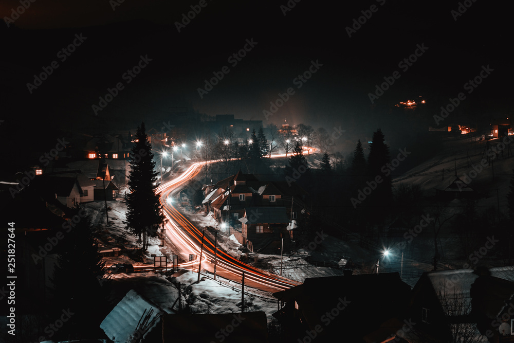 Magnificent night landscape of the Ukrainian village in bright light and blurred automobile lights