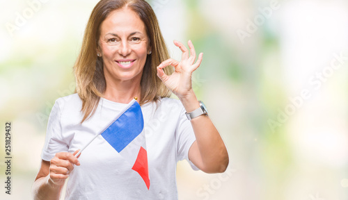 Middle age hispanic woman holding flag of France over isolated background doing ok sign with fingers, excellent symbol