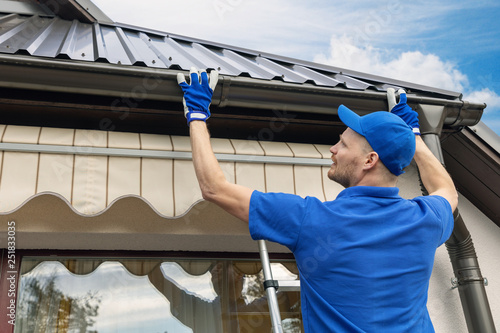 man installing house roof rain gutter system photo