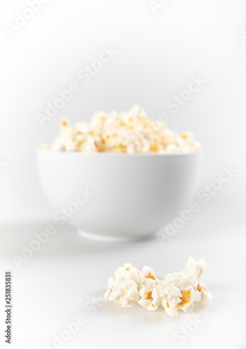 Bowl of fresh popcorn with a few popcorn in front focus on isolated