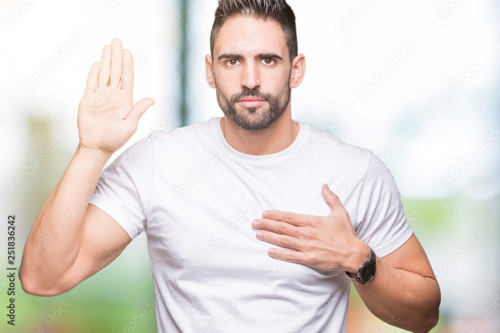 Handsome man wearing white t-shirt over outdoors background Swearing with hand on chest and open palm, making a loyalty promise oath Handsome man wearing white t-shirt over outdoors background Swearing with hand on chest and open palm, making a loyalty promise oath