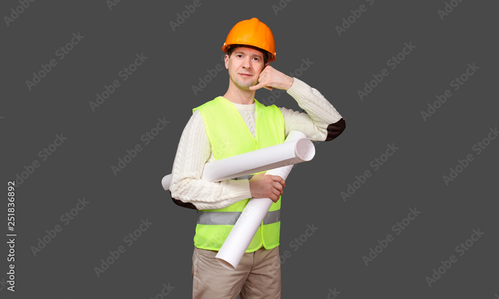 the civil engineer keeps a hand about an ear and a mouth in a helmet, the gesture - to phone, call, agree the civil engineer keeps a hand about an ear and a mouth in a helmet, the gesture - to phone, call, agree