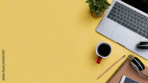 office workspace yellow desk table with laptop, coffee, mobile, notebook, plant. flat lay