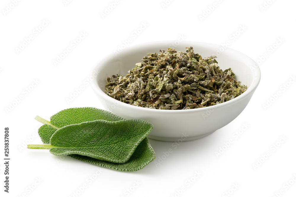 Dried rubbed sage in a white ceramic bowl next to fresh sage leaves isolated on white. Dried rubbed sage in a white ceramic bowl next to fresh sage leaves isolated on white.