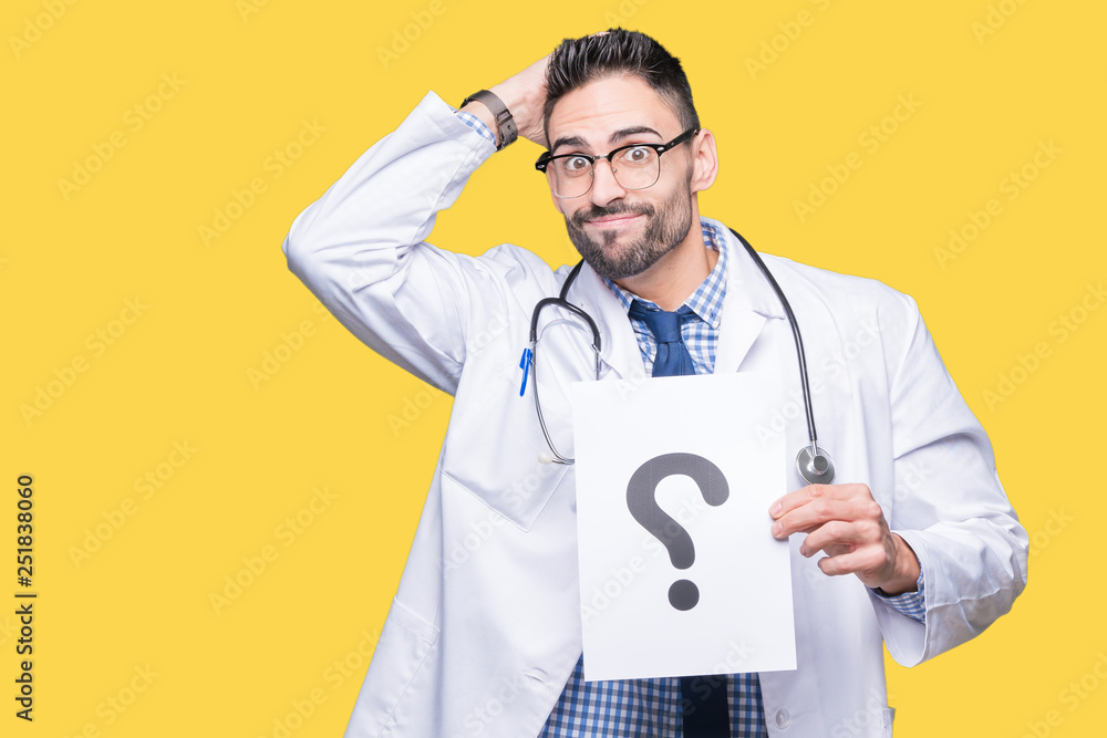 Handsome young doctor man holding paper with question mark over isolated background stressed with hand on head, shocked with shame and surprise face, angry and frustrated. Fear and upset for mistake. Handsome young doctor man holding paper with question mark over isolated background stressed with hand on head, shocked with shame and surprise face, angry and frustrated. Fear and upset for mistake.