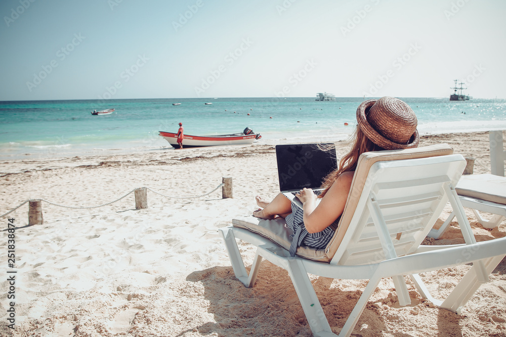 Freelance woman working on laptop on the beach with ocean view